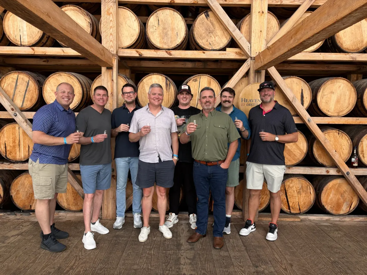 Members together in front of a wall of oak barrels.