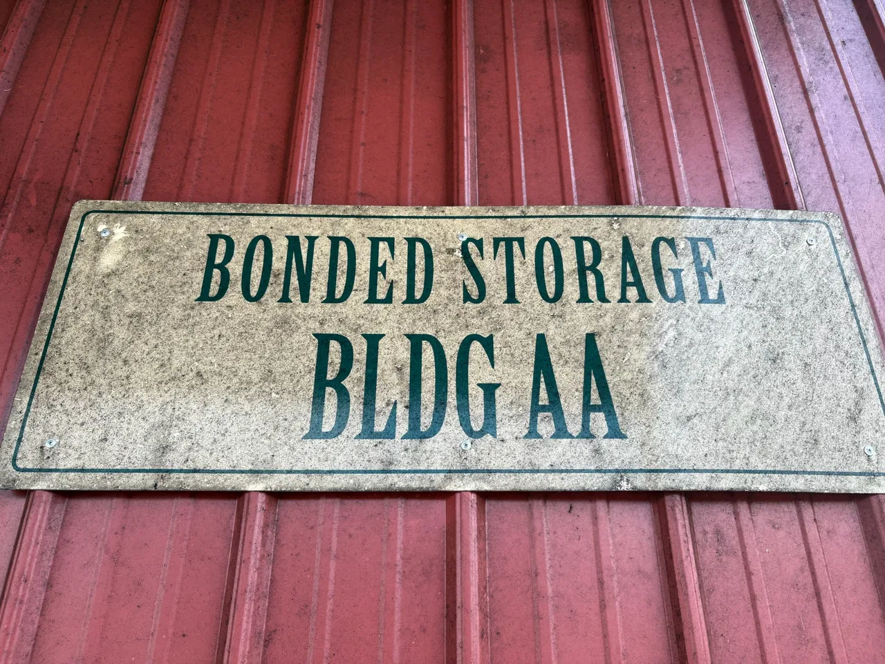 Bonded storage signage on a weathered red warehouse door at Buffalo Trace.